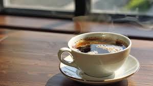 Quiet morning scene with a cup of tea on a wooden table beside a soft-lit window